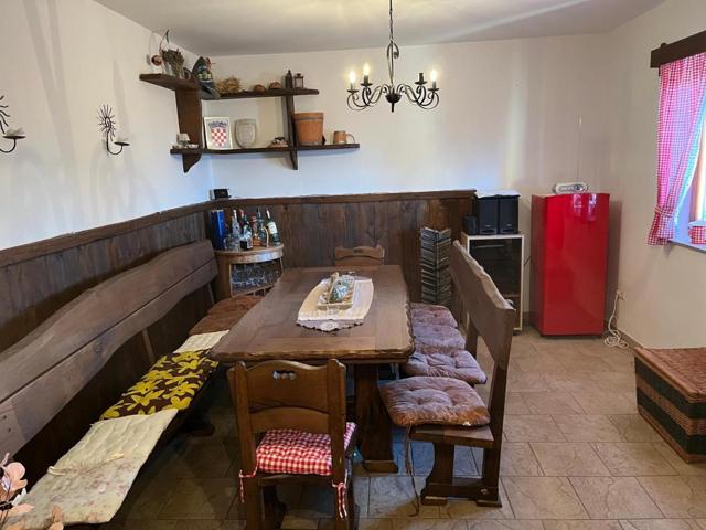 Long wooden dining table with benches and a red fridge