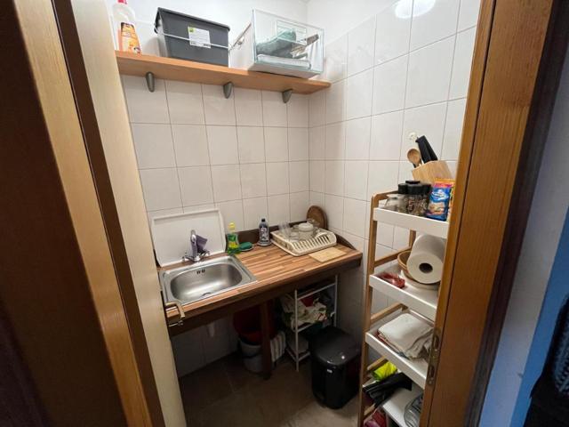 Small tiled kitchen with sink and shelves