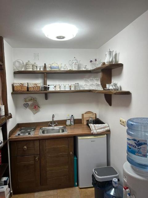 Kitchenette with sink, shelves, small fridge and water cooler